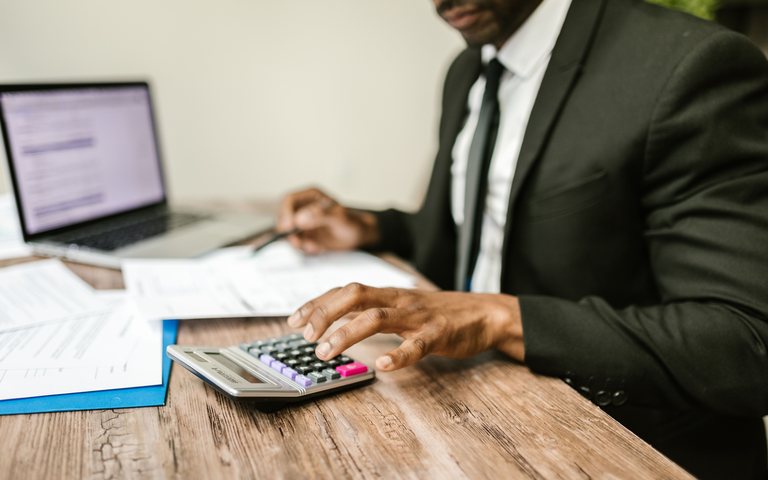 Deux personnes travaillent ensemble sur un dossier, calculatrice et documents.